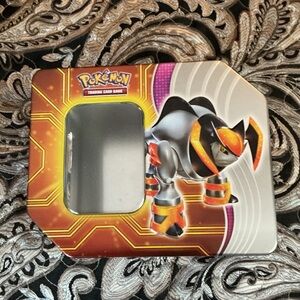 Pokemon Tin with Orange and Black with some cards.